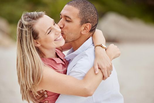 Smile, love and happy couple kiss on the cheek on honeymoon vacation outdoors to celebrate their marriage. Happiness, interracial and smiling woman enjoys traveling on romantic trip with her partner
