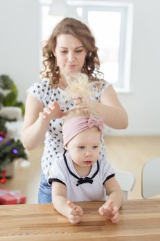 Mother doing hair for daughter with cochlear implant hearing aid - diversity concept. Innovative medical technologies