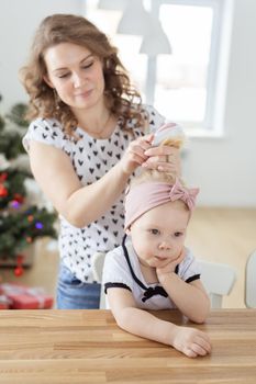 Mother doing hair for daughter with cochlear implant hearing aid - diversity concept. Innovative medical technologies