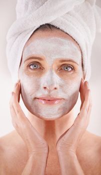 Pampering her skin with a face mask. Cropped portrait of a beautiful mature woman applying a mask to her face.