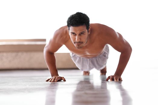 Pushing himself to performance perfection. Full length shot of a determined man doing push-ups.