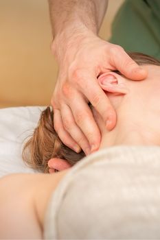Osteopath doing massage on the female head in rehabilitation clinic center.