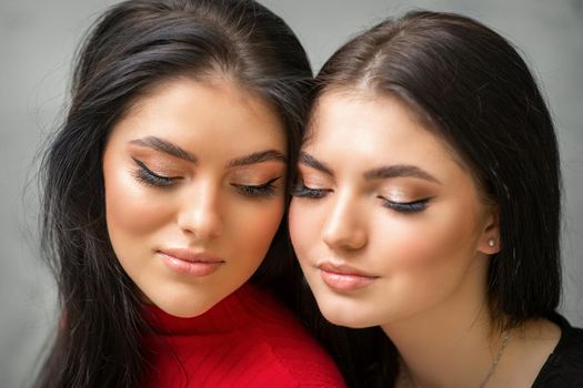 Portrait of young beautiful two women with long lashes and closed eyes after eyelash extensions.