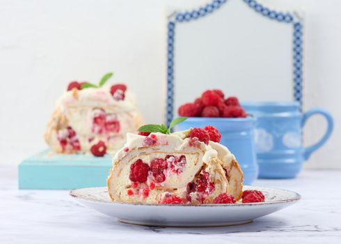 Baked meringue roll with cream and fresh red raspberry, white background	
