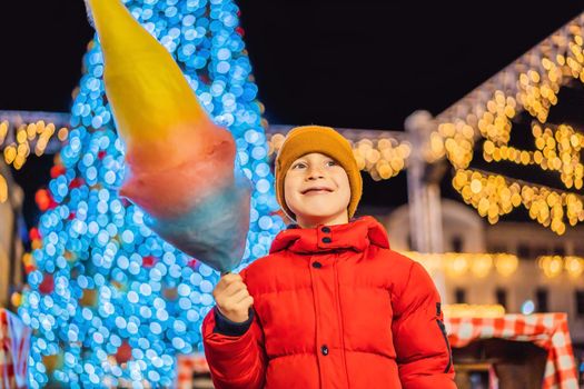 Boy with cotton candy at christmas market. Happy child on Christmas market. Traditional leisure for families on xmas
