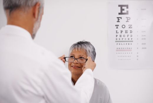 A new pair of eyes. an optometrist putting a pair of glasses on a patient.