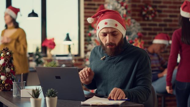 Male employee wearing santa hat in festive office