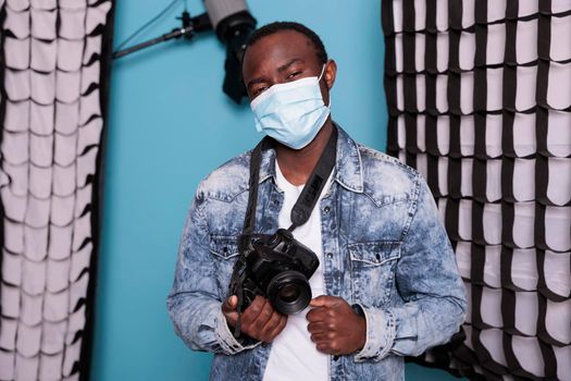 African american photographer with professional camera wearing virus protection facemask