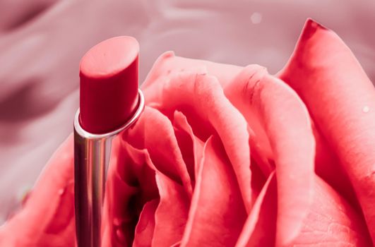 Pink lipstick and rose flower on liquid background, waterproof glamour make-up and lip gloss cosmetics product for luxury beauty brand holiday design