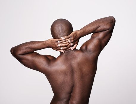 Even his back is muscular perfection. Rearview shot of a muscular african american man stretching.