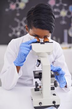 Careful analysis and observation. A young scientist using a microscope in her lab.
