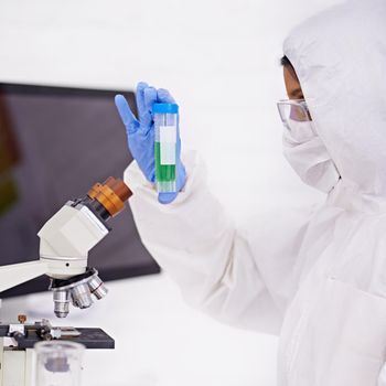 What do we have here. A young scientist in protective clothing examining a test tube.
