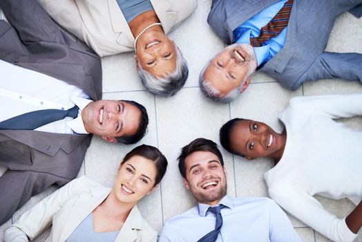 Do you want to join the circle of trust. High angle portrait of a group of diverse businesspeople lying on the floor in a circle.
