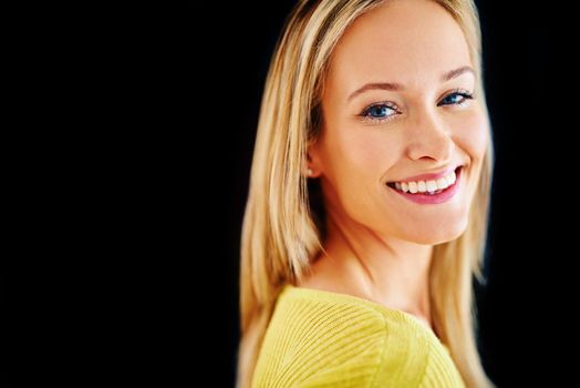 Create your own sunshine. Studio portrait of a beautiful young blonde woman isolated on black.