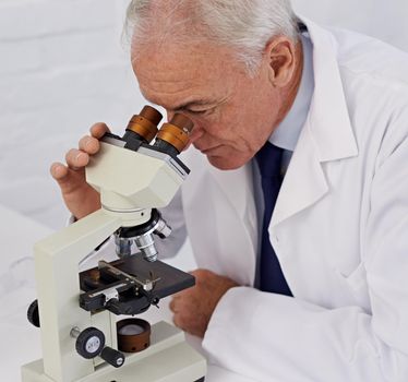 He has a keen eye for science. a mature scientist using a microscope.