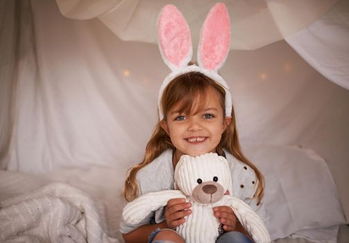 My furry friend. Portrait of an adorable little girl wearing bunny ears and holding her toy rabbit.