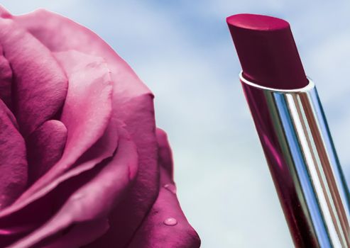 Purple lipstick and rose flower on liquid background, waterproof glamour make-up and lip gloss cosmetics product for luxury beauty brand holiday design