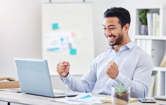 Motivation, success and yes with a business man in celebration and working on a laptop by his desk in the office. Email, good news and smile with a young and happy male employee cheering at work