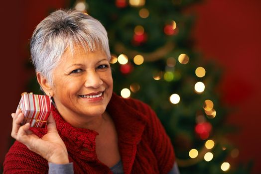 I wonder whats inside...a mature woman holding a christmas present to her ear.