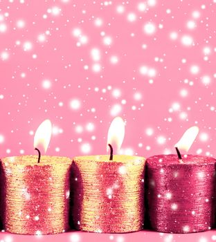 Christmas candles and shiny snow on pink background, holiday season decoration