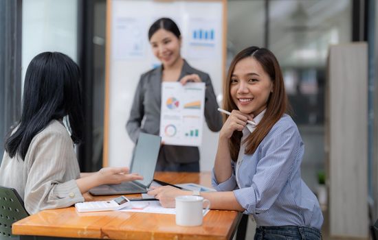 Portrait of businesswoman smart casual wear looking at camera and smile with digital table in modern office workplace. Young Asia lady standing relax in contemporary meeting room.