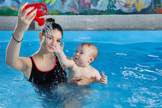 Little baby learning to swim in pool with teacher
