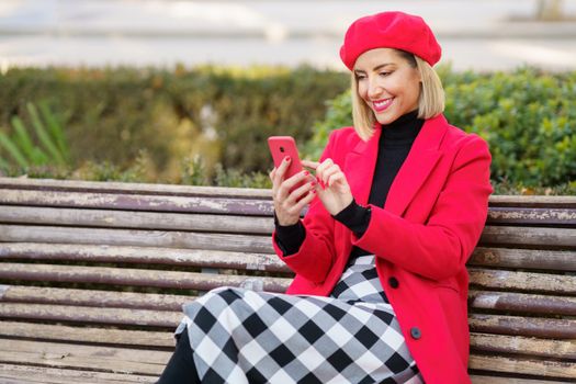 Smiling woman surfing smartphone on bench