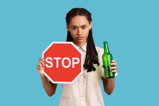 Woman holding red stop sign and bottle with alcoholic beverage, calls on dont drink alcohol.