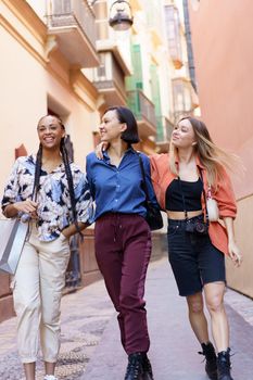 Carefree multiracial women enjoying free time against city building