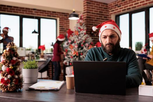 Businessman with santa hat working on laptop