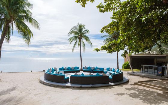 Tropical beach with palm trees and beach chairs on a white beach in Hua Hin Thailand