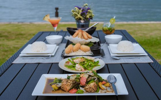 Luxury dinner table by the ocean with lobster, fish and thai food