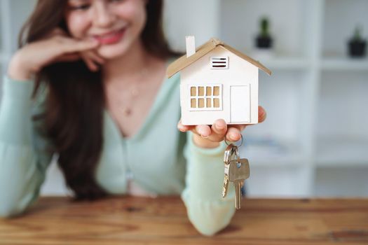 The customer holds the house model and keys