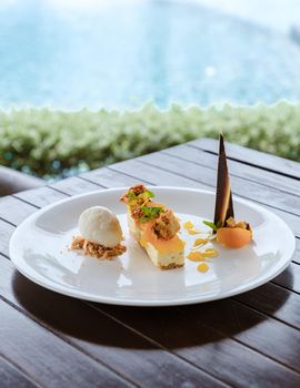 coconut ice cream dessert and mango cake on a plate by a pool