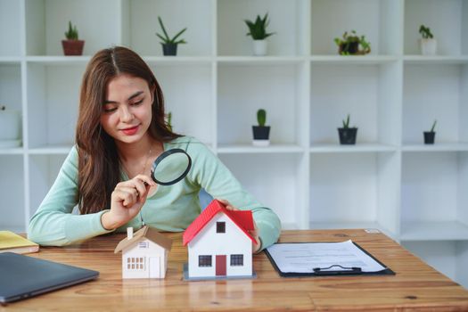 Customer holding a magnifying glass to select a house model, residential inspection concept