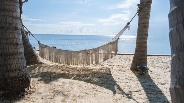 White hammock under palm trees at a tropical beach in Thailand Hua Hin