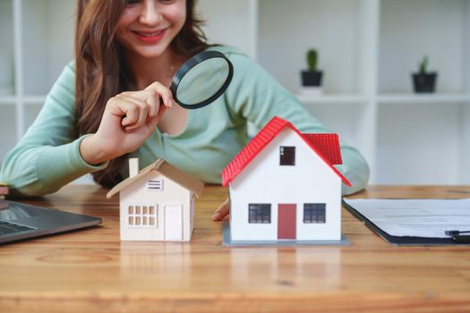 Customer holding a magnifying glass to select a house model, residential inspection concept