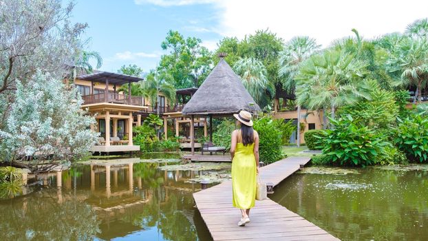 Asian women with a hat walking at a tropical garden during vacation
