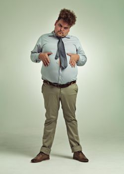 Want some of this. Full length shot of an overweight man holding his rotund belly.