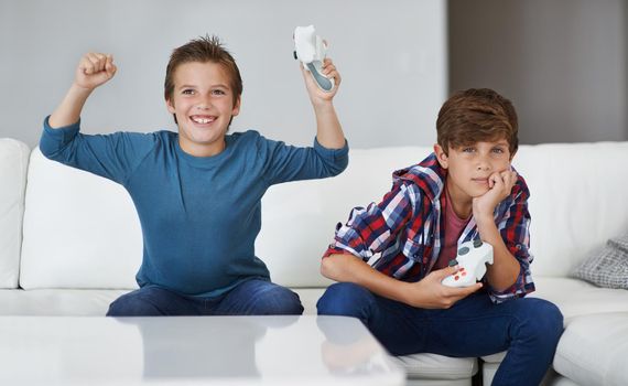 I won again. a young boy celebrating while his friend looks upset at losing a video game.