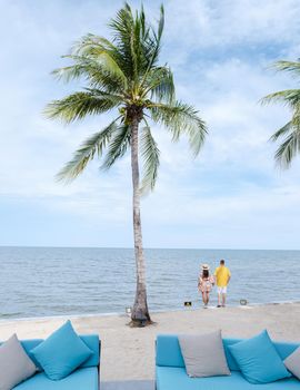 Men and women walking on a tropical beach with palm trees in Hua Hin Thailand