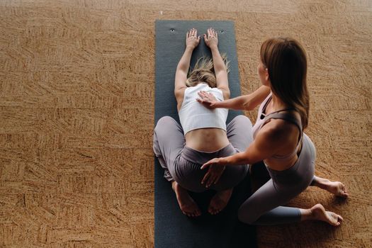 Yoga exercises. A personal trainer teaches a woman yoga classes in the gym.