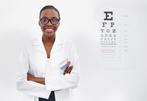 Lets test those eyes. Portrait of a female optometrist standing beside a eye test chart.