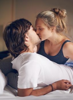 Waking up with a kiss. an affectionate young couple kissing in bed.