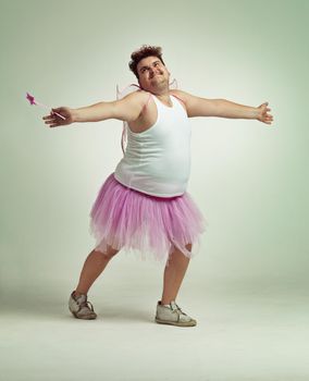 Come in for a hug. An overweight man comically dressed-up in a pink fairy costume.