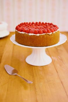 Just waiting for an eager taste tester. a delicious cheese cake topped with cream and fresh raspberries.