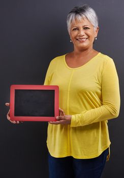 Like my new tablet pc. Portrait of a mature woman holding a digital tablet in a studio.