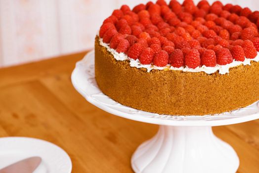 This cake is looking for some company. a delicious cheese cake topped with cream and fresh raspberries.