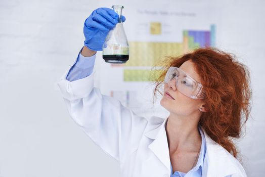 This could be the solution. A cropped shot of a young frizzy-haired scientist examining a flask in her lab.