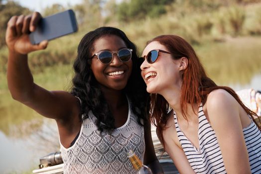 Sharing a sunshine moment. two women snapping selfies on holiday.